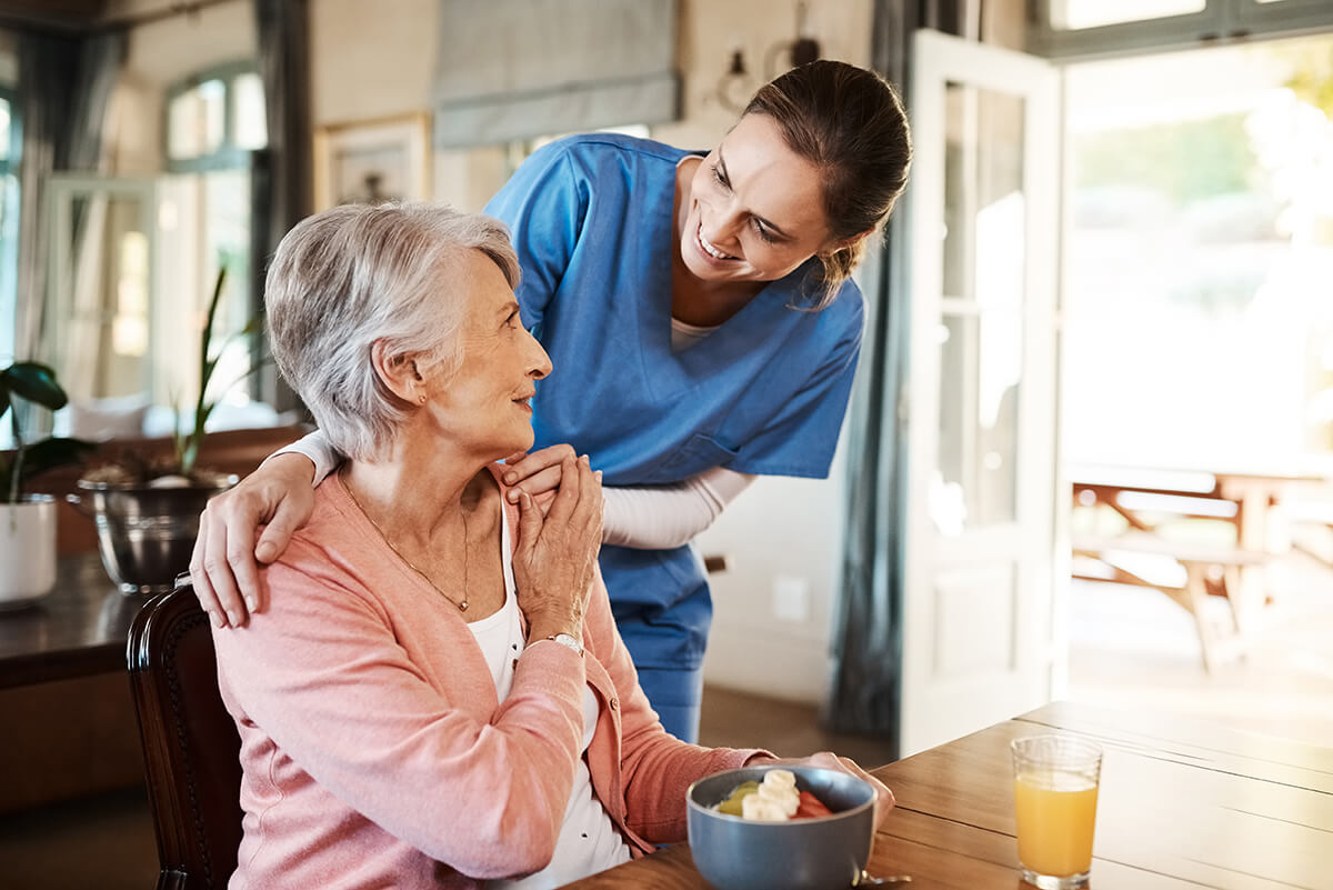 Healthcare, elderly woman with nurse with breakfast at her home and at the table in living room